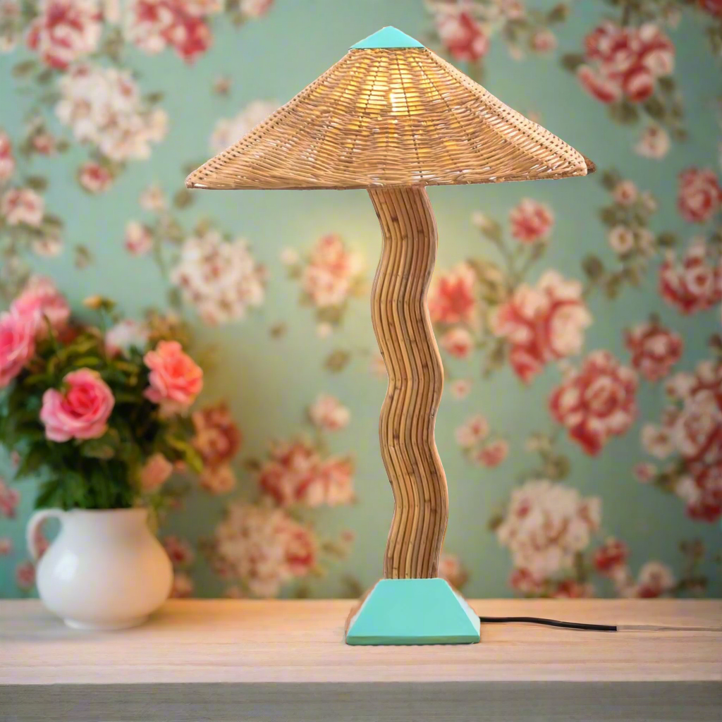 A stylish table lamp with a geometric design, featuring a wicker shade and a curved wooden base, predominantly in brown color, with a red switch and base.