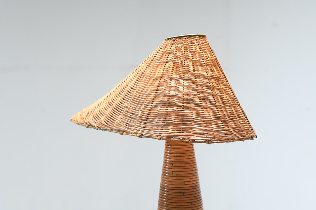 A natural woven rattan lampshade with a matching conical woven stem, shown against a plain light gray background.