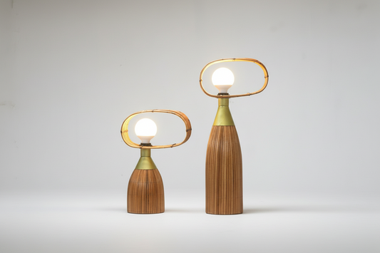 Two modern table lamps with wooden bases and metal loops on a wooden surface against a gray background.