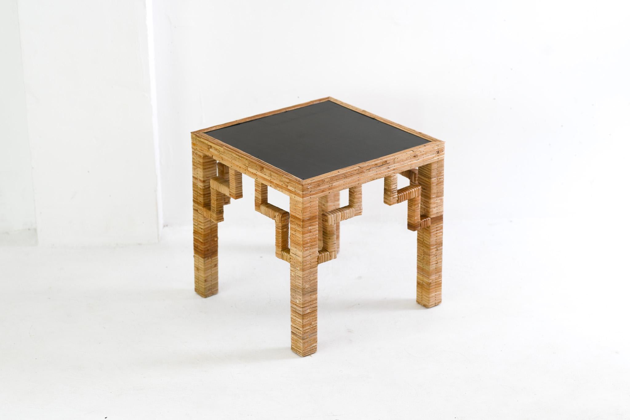 Small table with a black top and wicker frame on a white background