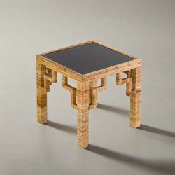 Square table with woven wooden frame and black top on a plain background