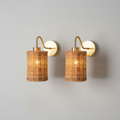 Pair of wicker and brass wall sconces on grey background