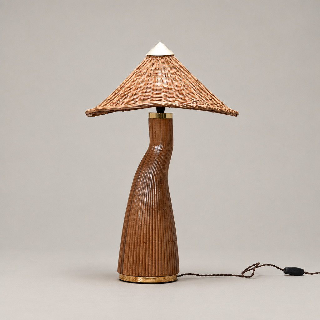 Warm-gray studio photo: “Shroom rattan table lamp with a woven conical shade and curved base on a warm-gray background.”
